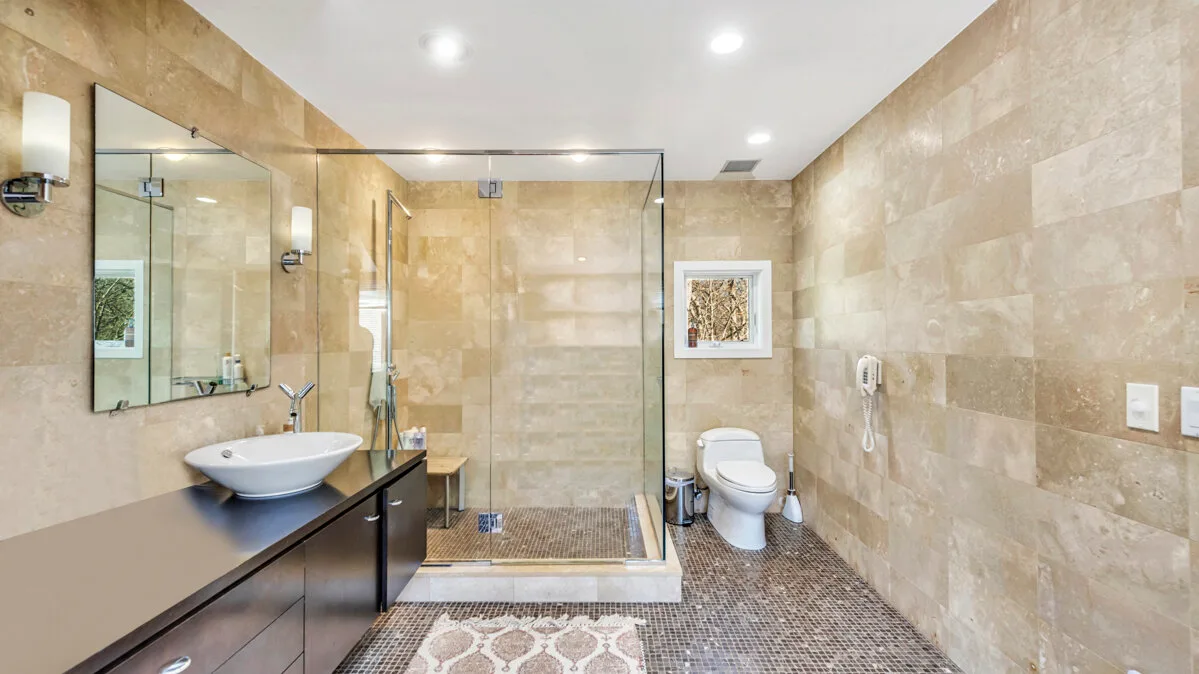 A tiled bathroom with a glass shower and a sink vanity.