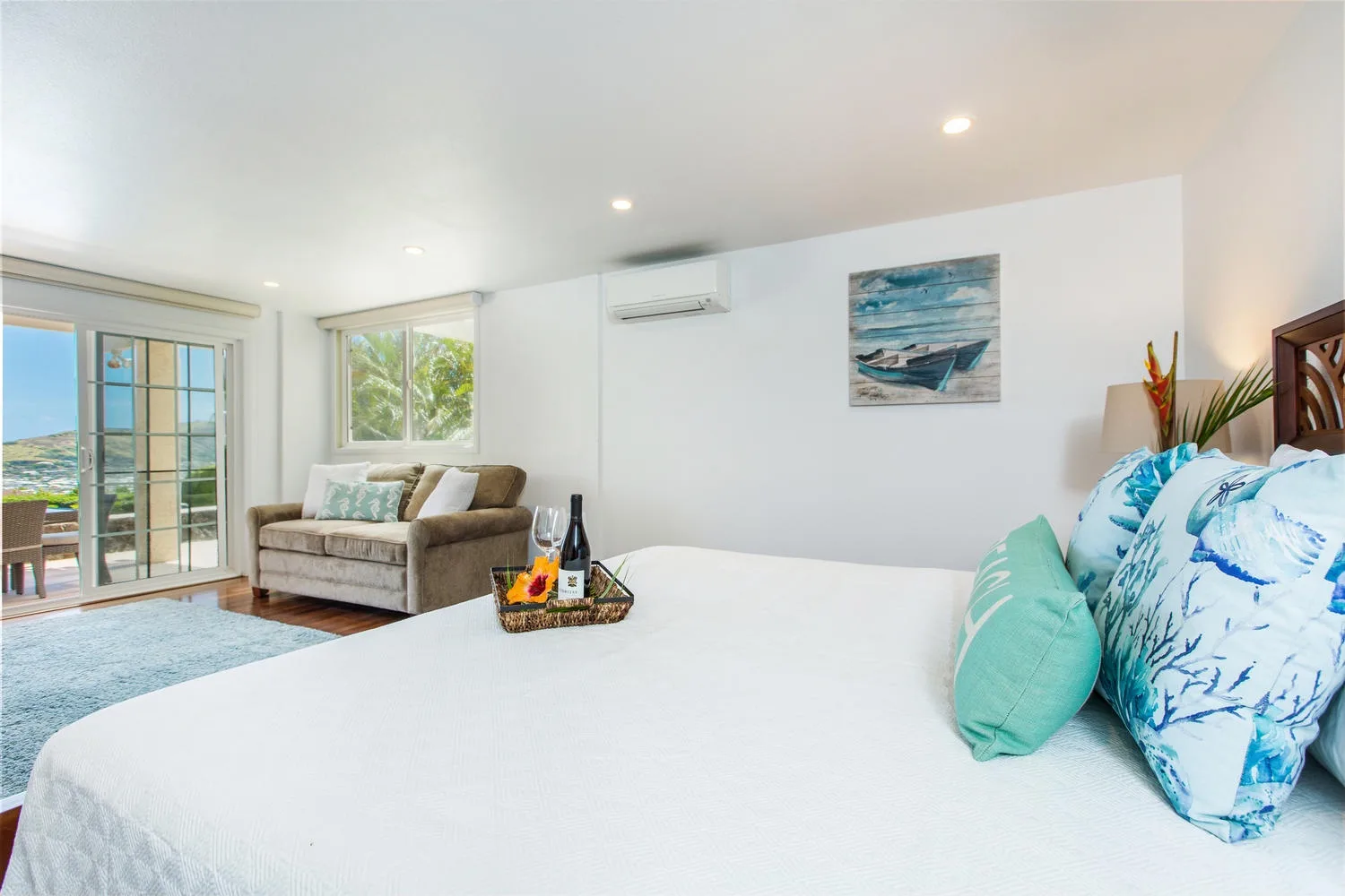 Un dormitorio luminoso con una cama grande, una zona de estar y una puerta corrediza de vidrio.