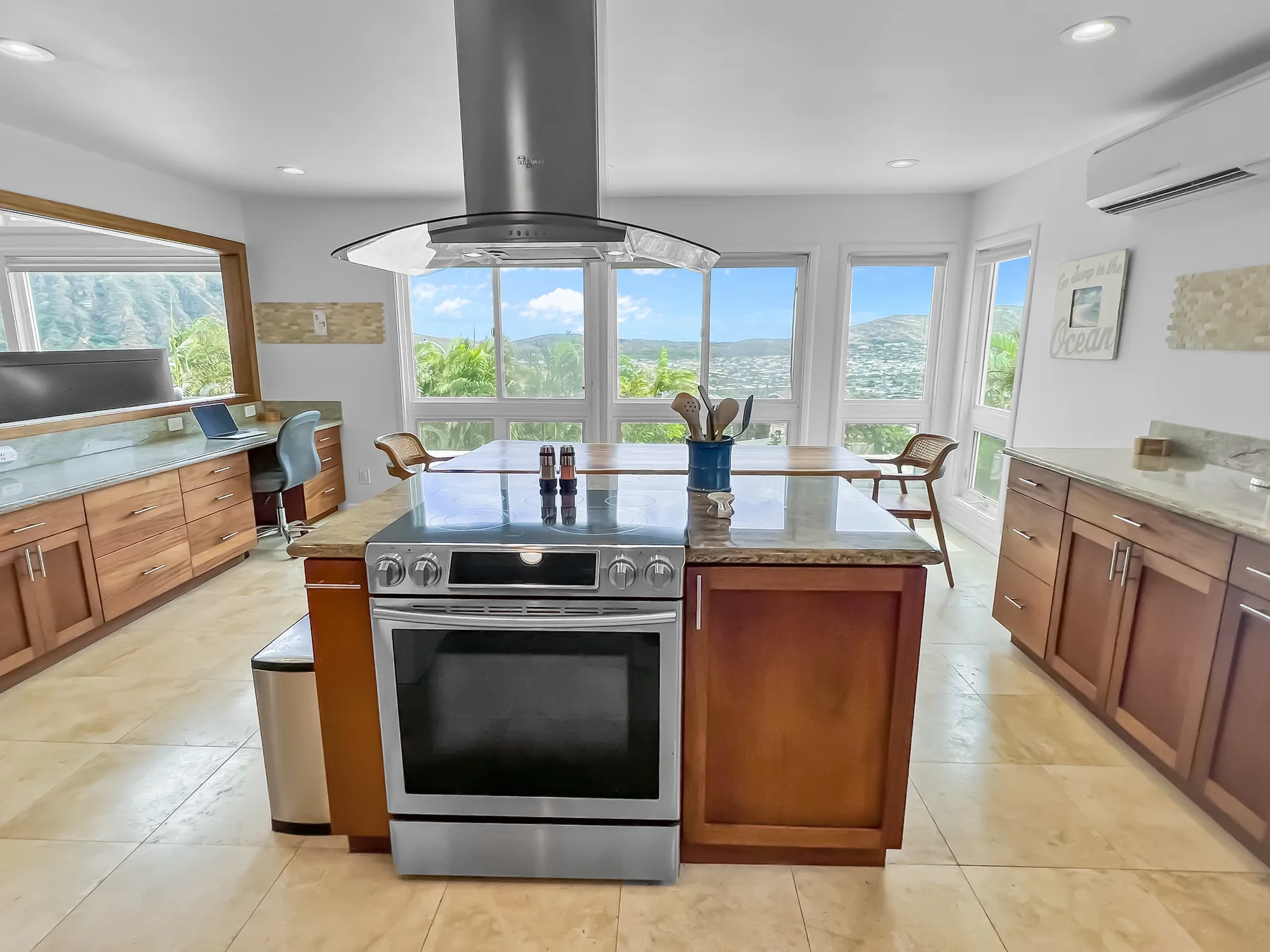 Una cocina luminosa con una isla central y grandes ventanas con vistas a un paisaje verde.