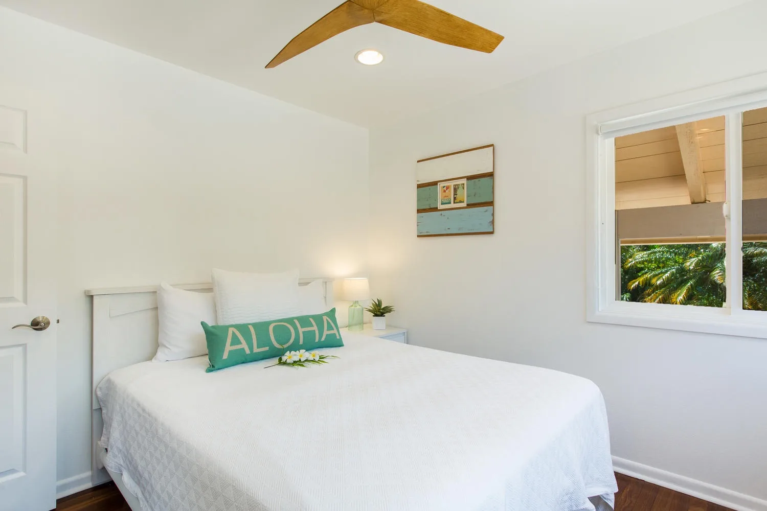 Un dormitorio luminoso con una cama bien hecha y una ventana con vistas a la vegetación.