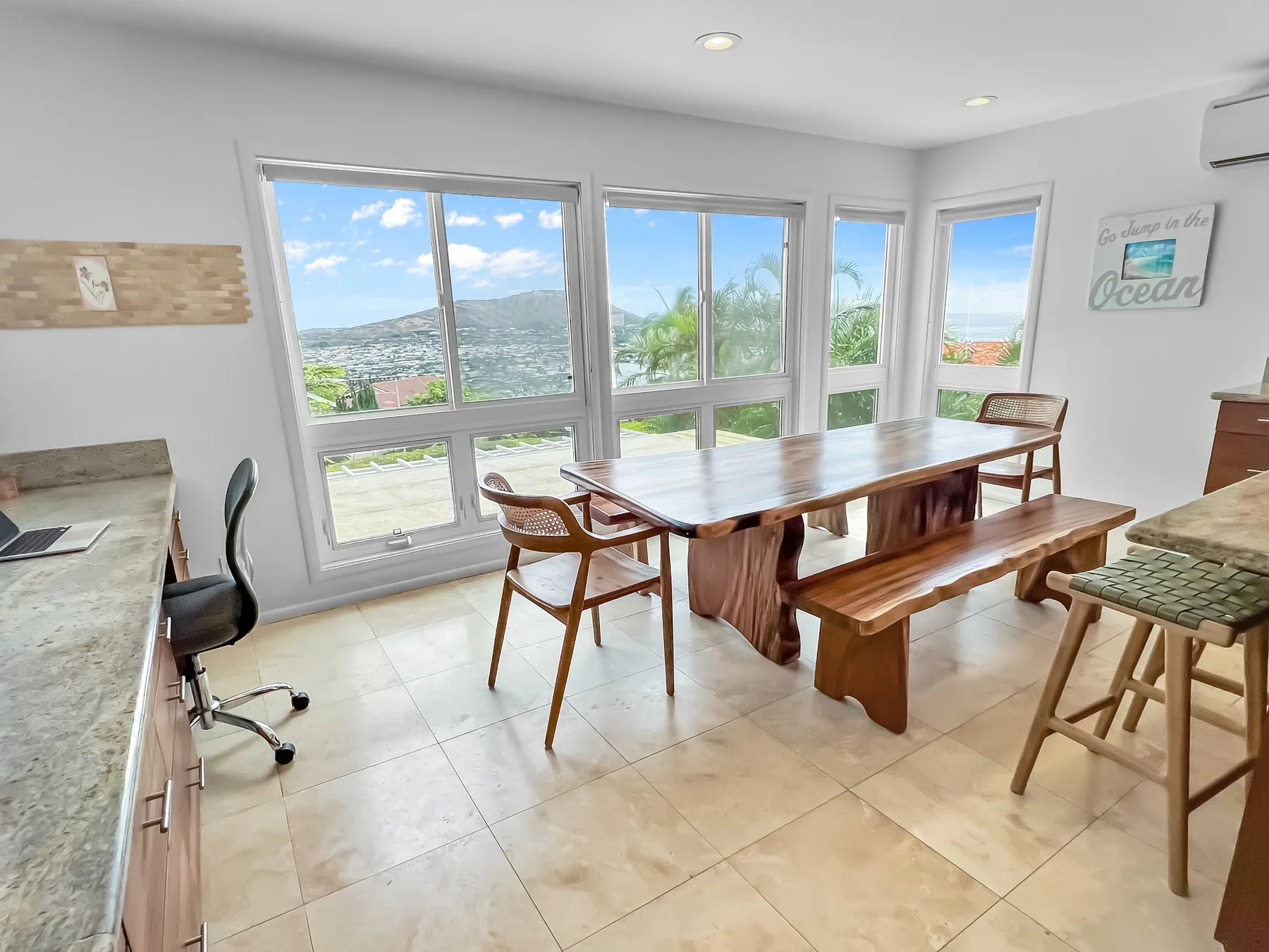 Un comedor luminoso con una mesa de madera y amplias ventanas con vistas a la ladera.