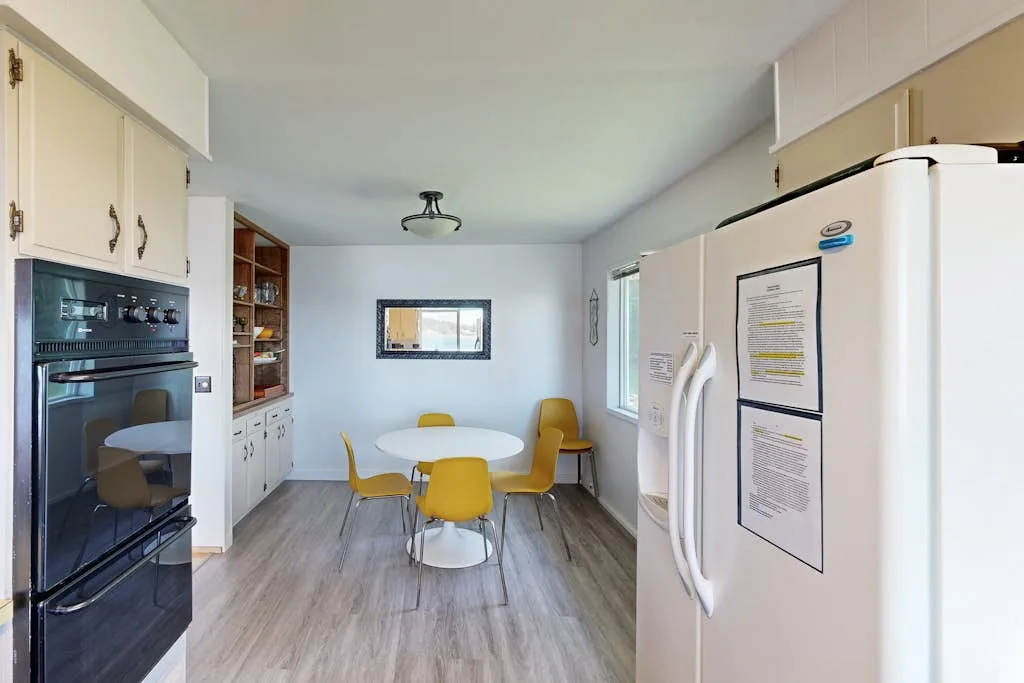 Una cocina luminosa con una mesa de comedor y asientos junto a los electrodomésticos.