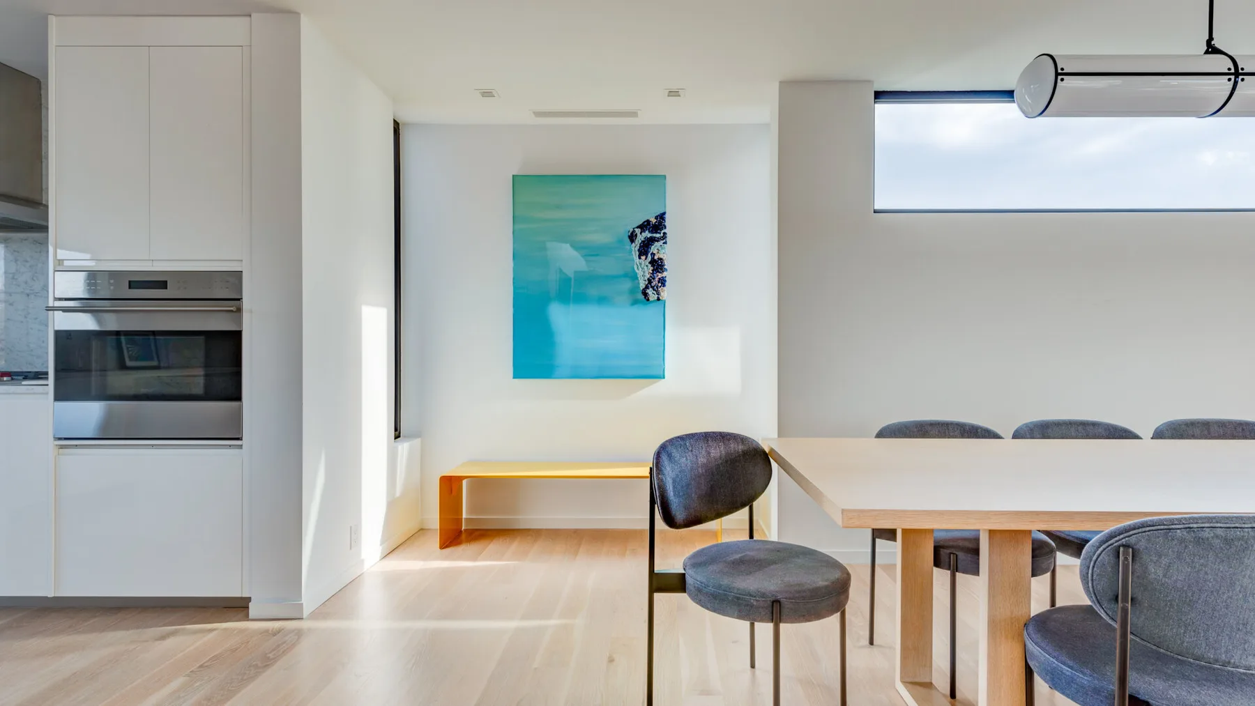 A bright dining area with a long table and colorful wall art.
