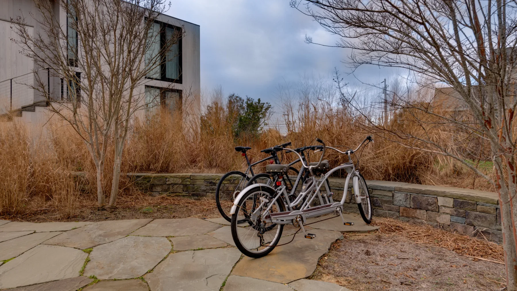 Bicycles are parked on a stone-paved path beside a low stone wall.