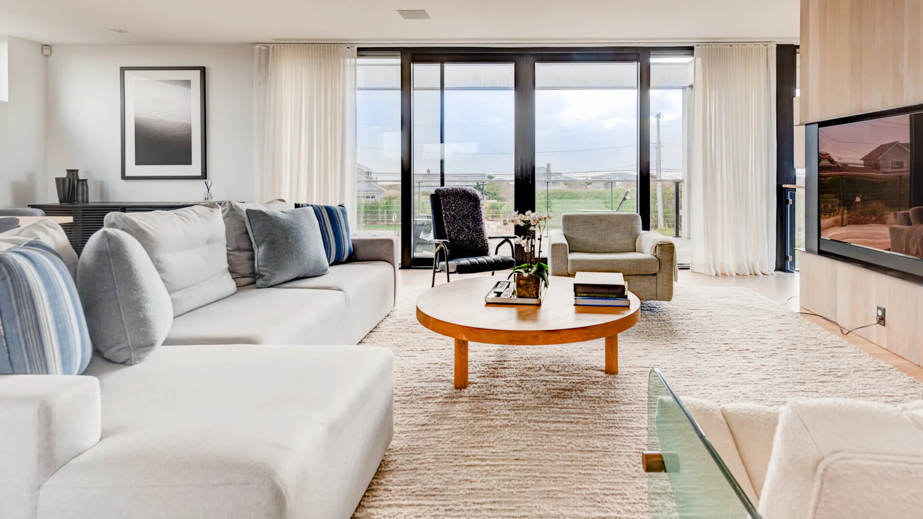 Una sala luminosa con asientos alrededor de una mesa de centro y grandes ventanas.