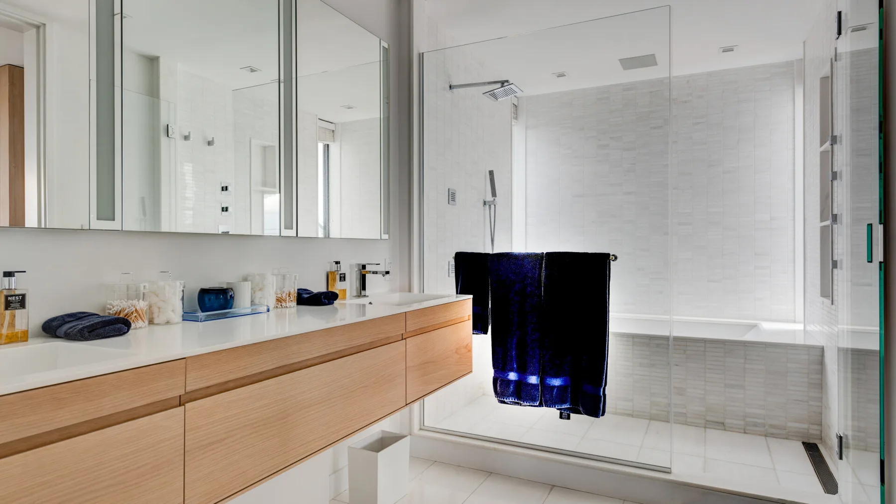 A bright bathroom with a long vanity and a glass-enclosed shower.