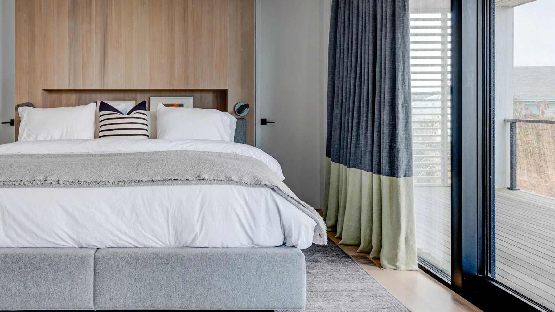 A bright bedroom with a neatly made bed beside a large glass door.