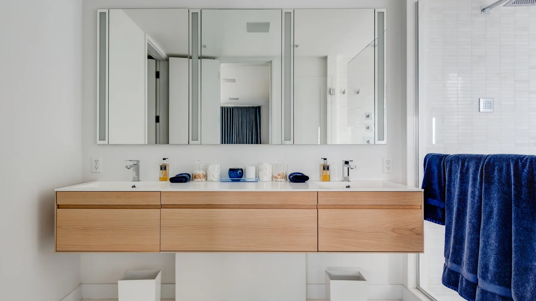 A bathroom vanity with a wide mirror and blue towels hanging nearby.