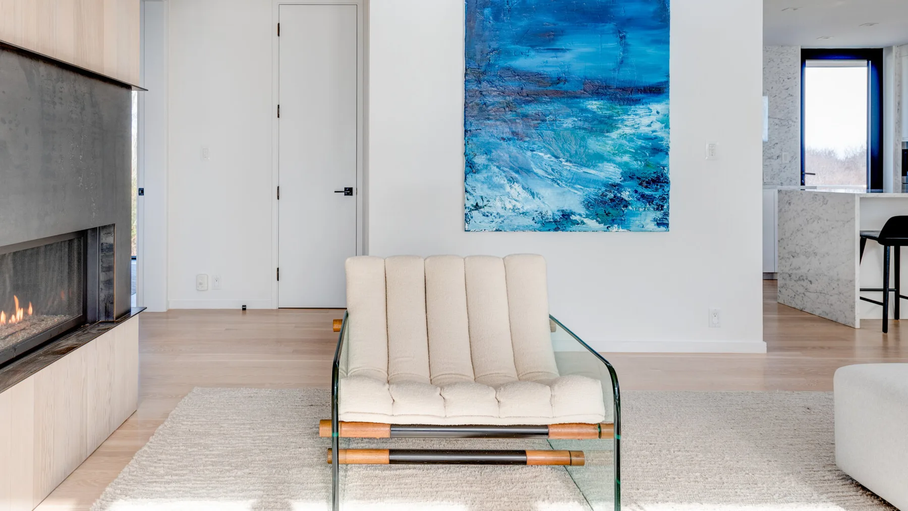 A bright living room with cream seating and a blue abstract painting.