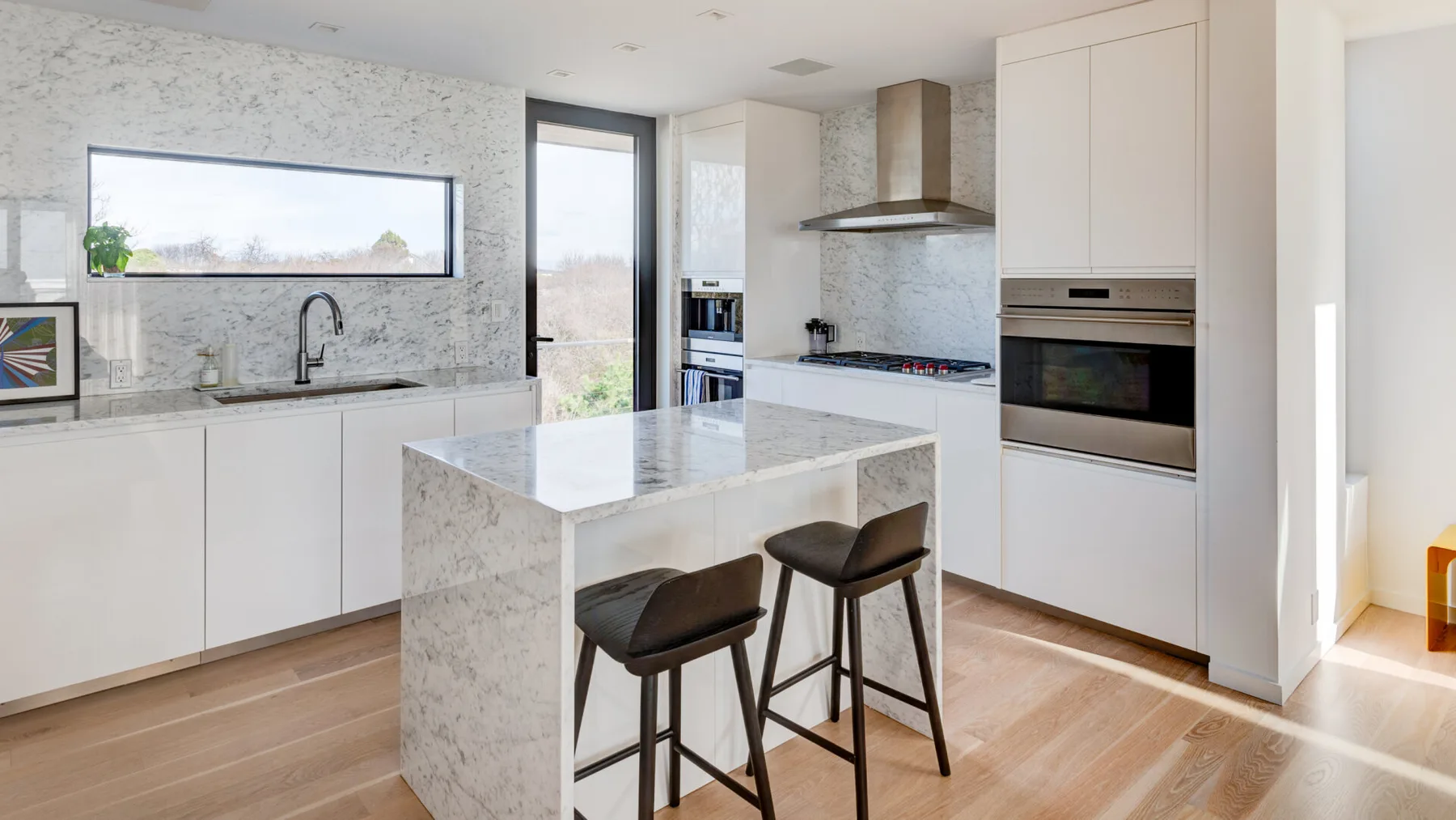 A bright kitchen with a stone island and two bar stools.