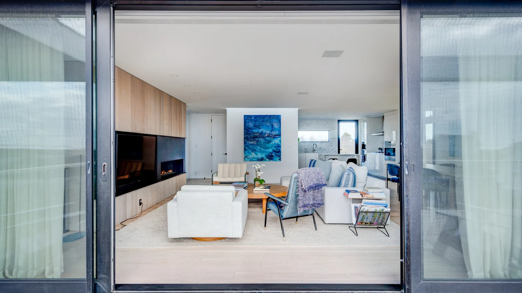 A bright living room opens onto a balcony through wide glass doors.
