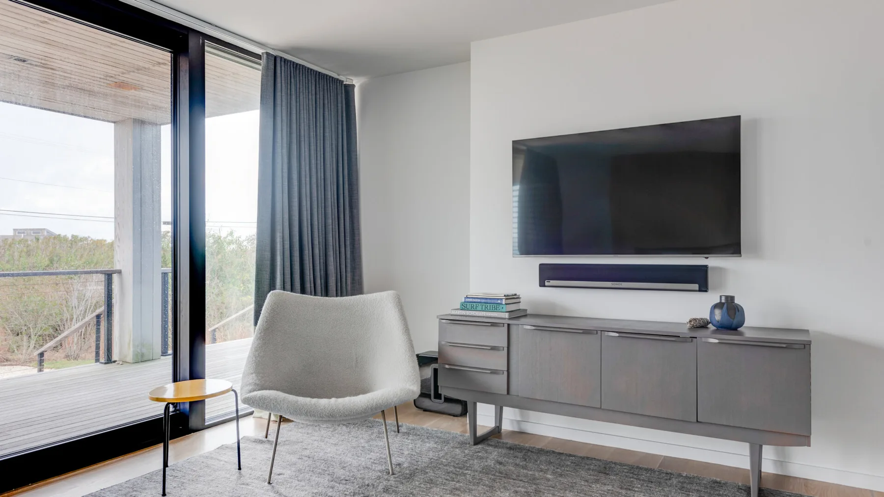 A modern living area with a television, seating, and a large window.