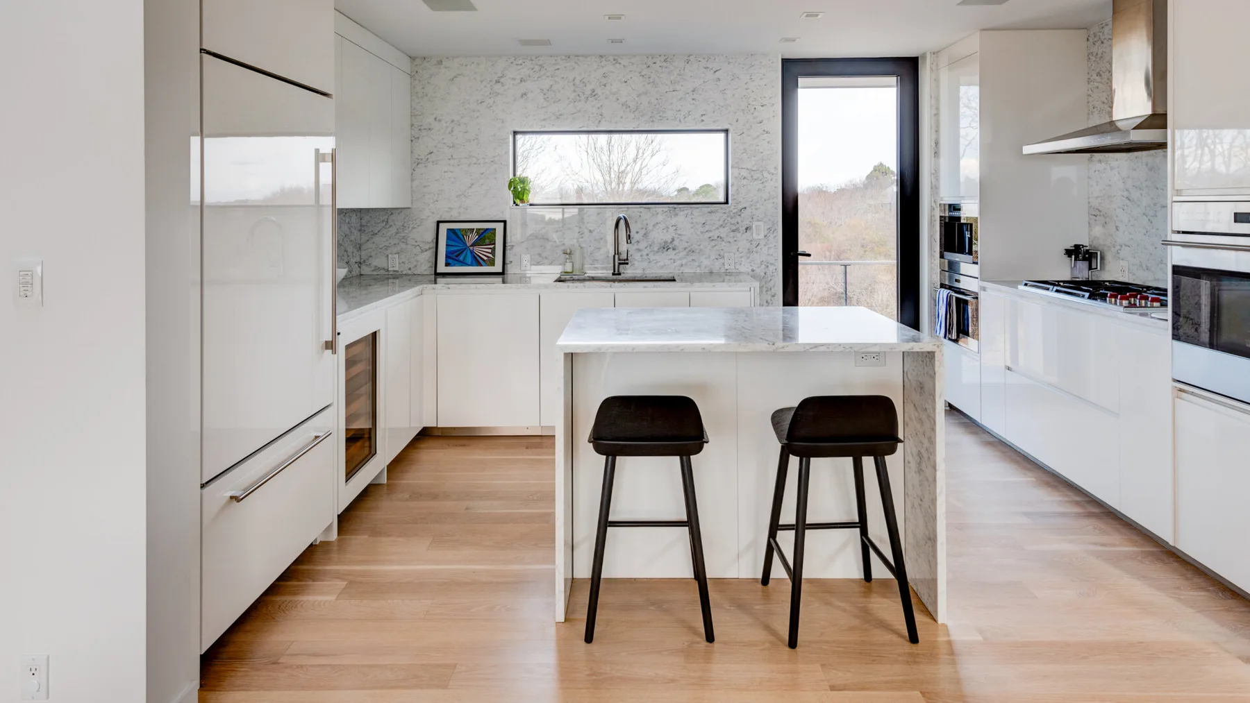 A bright modern kitchen with a central island and two stools.