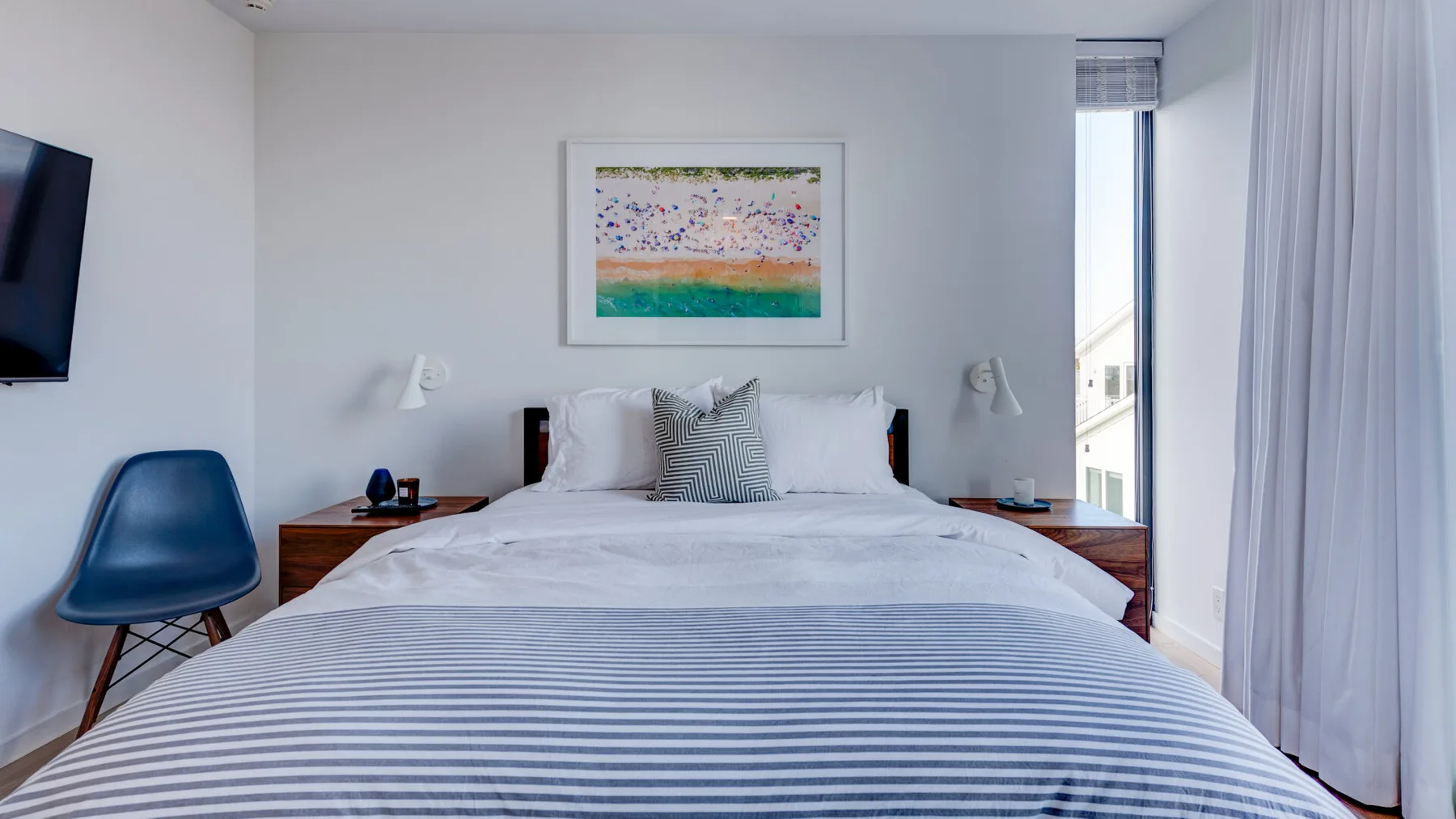 A bedroom with a neatly made bed and framed artwork above the headboard.