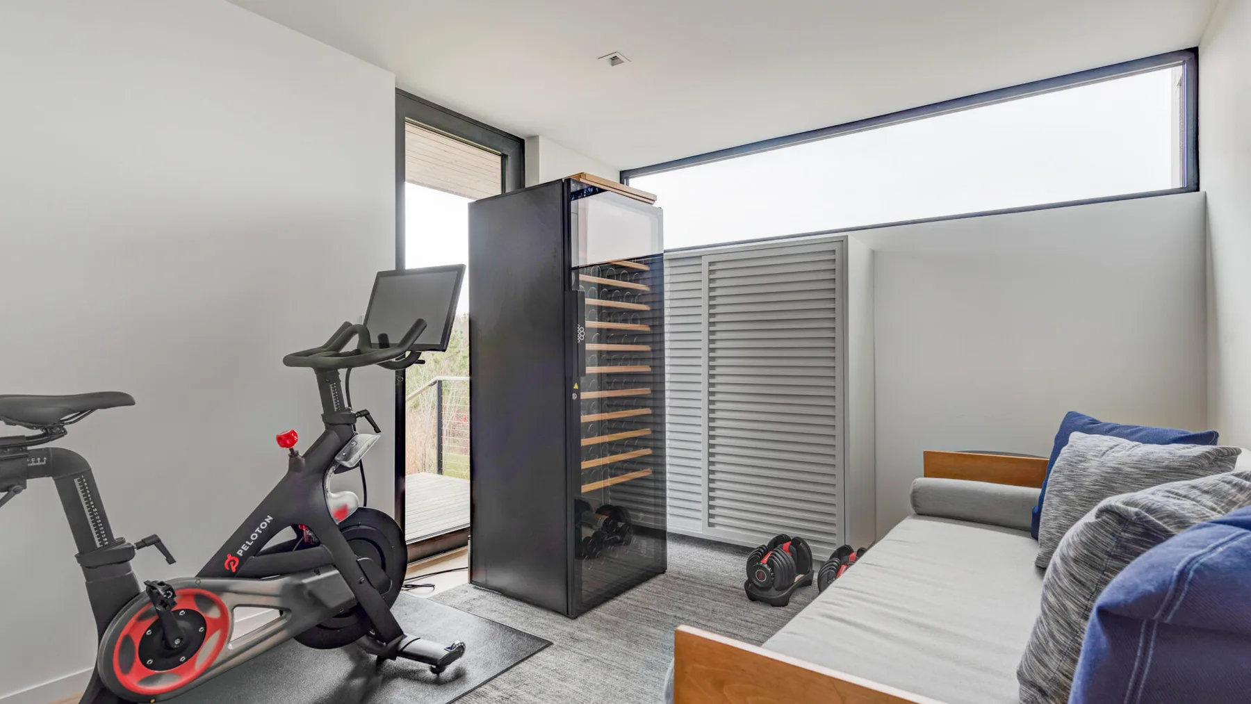 A bedroom with a stationary exercise bike and a bed beside the window.