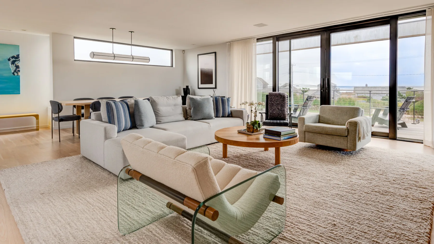 Una sala luminosa con asientos, una mesa de centro y grandes ventanas con vistas al exterior.