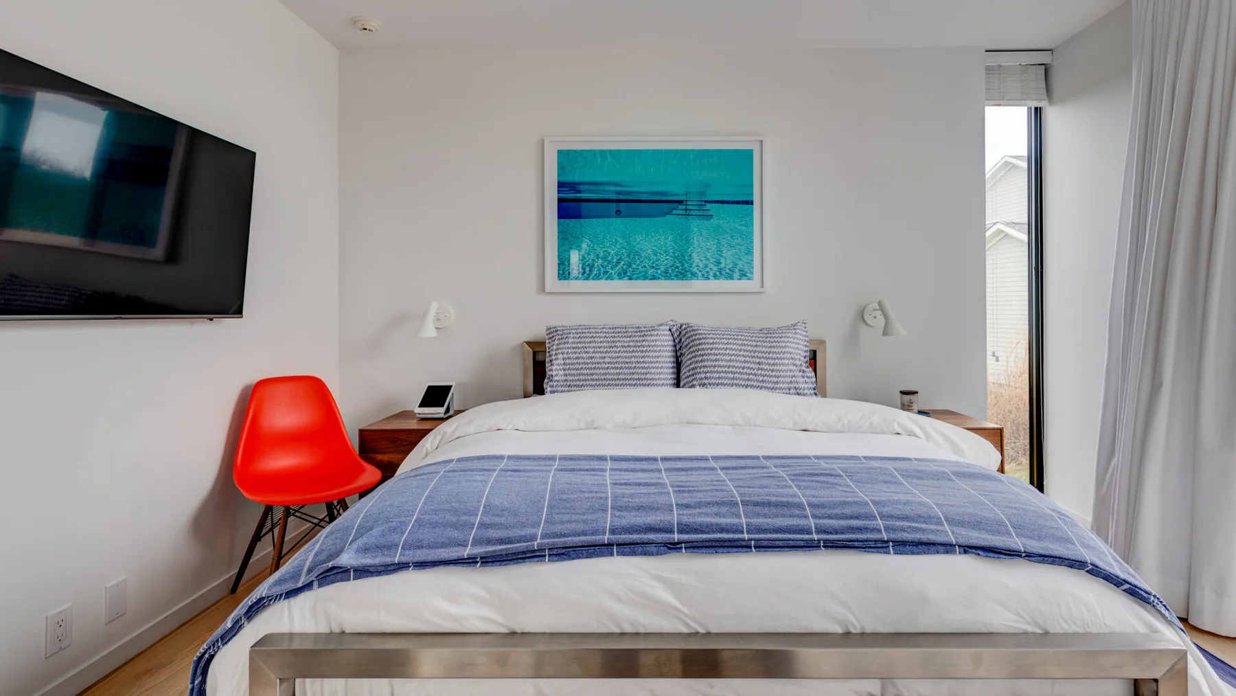 A bedroom with a neatly made bed and a framed picture above it.