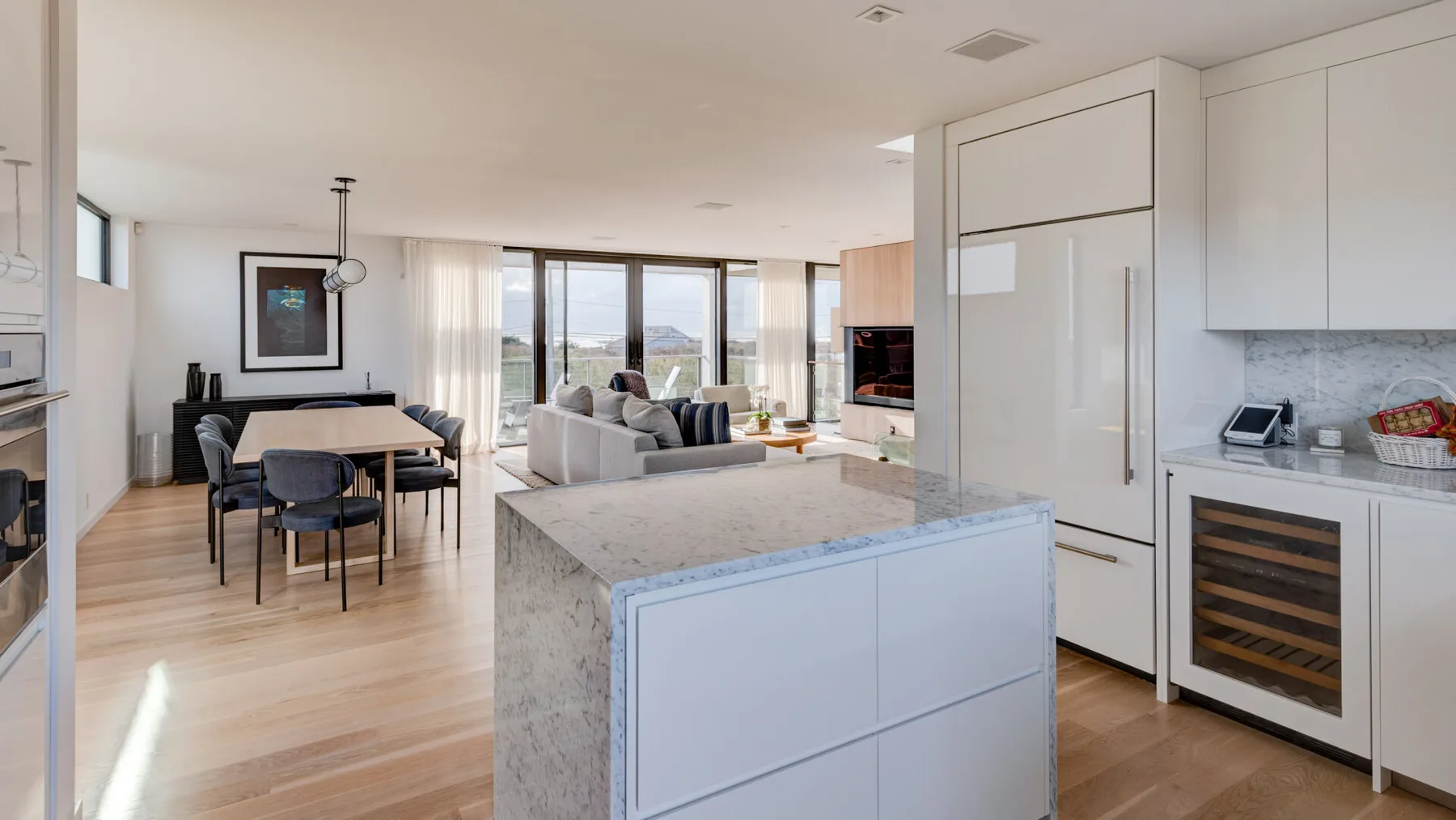 An open-plan living and dining area has large windows and a central kitchen island.