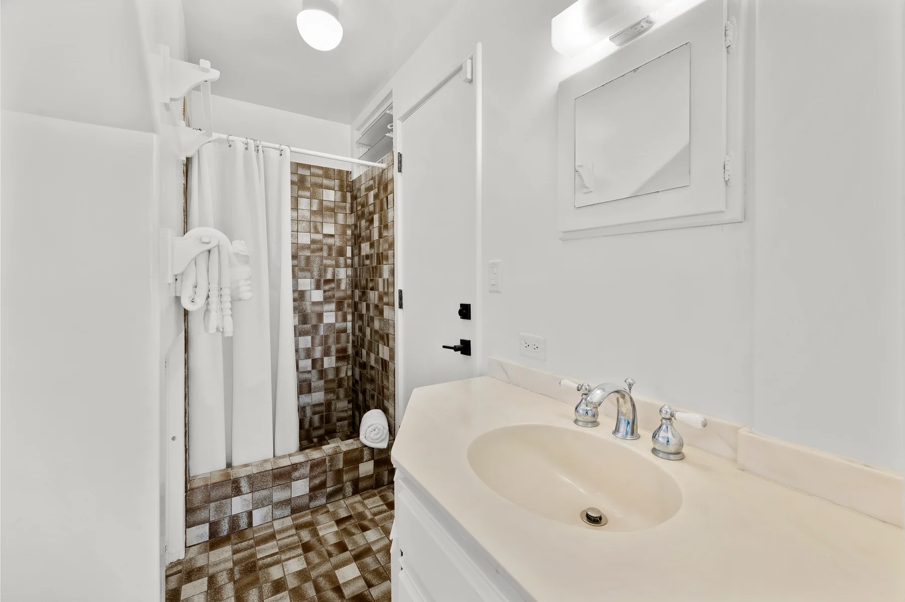 A bright bathroom with a sink vanity and a curtained shower.