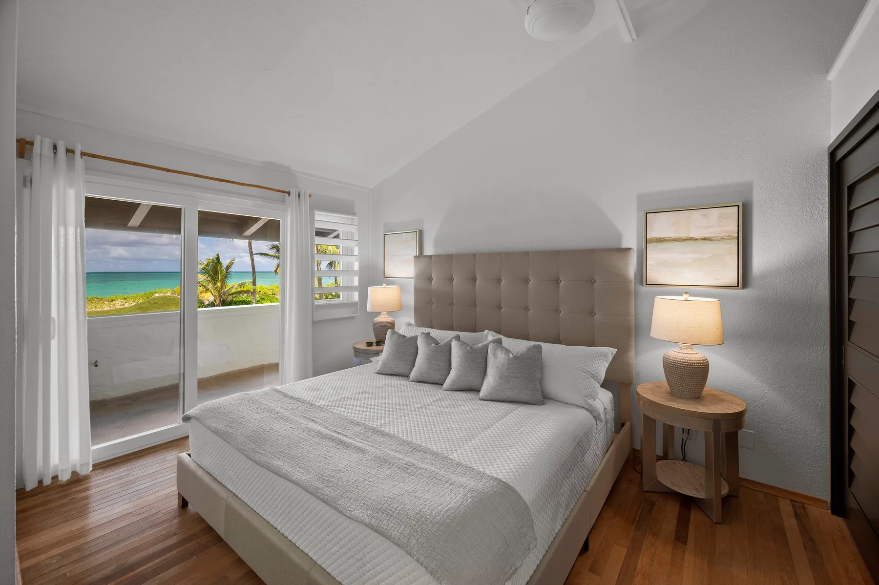 A bedroom with a large bed, bedside tables, and sliding glass doors opening to a balcony.