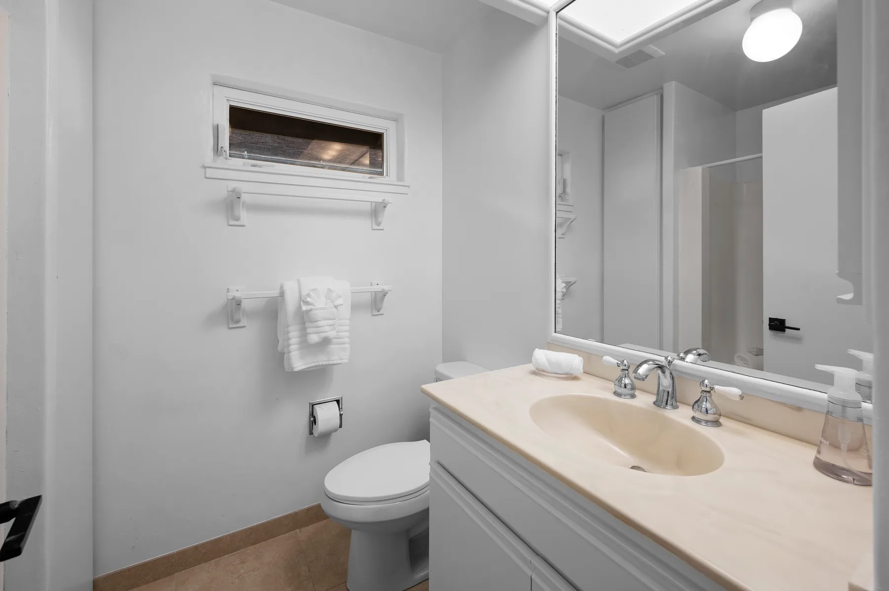 A bright bathroom with a vanity, sink, and toilet.