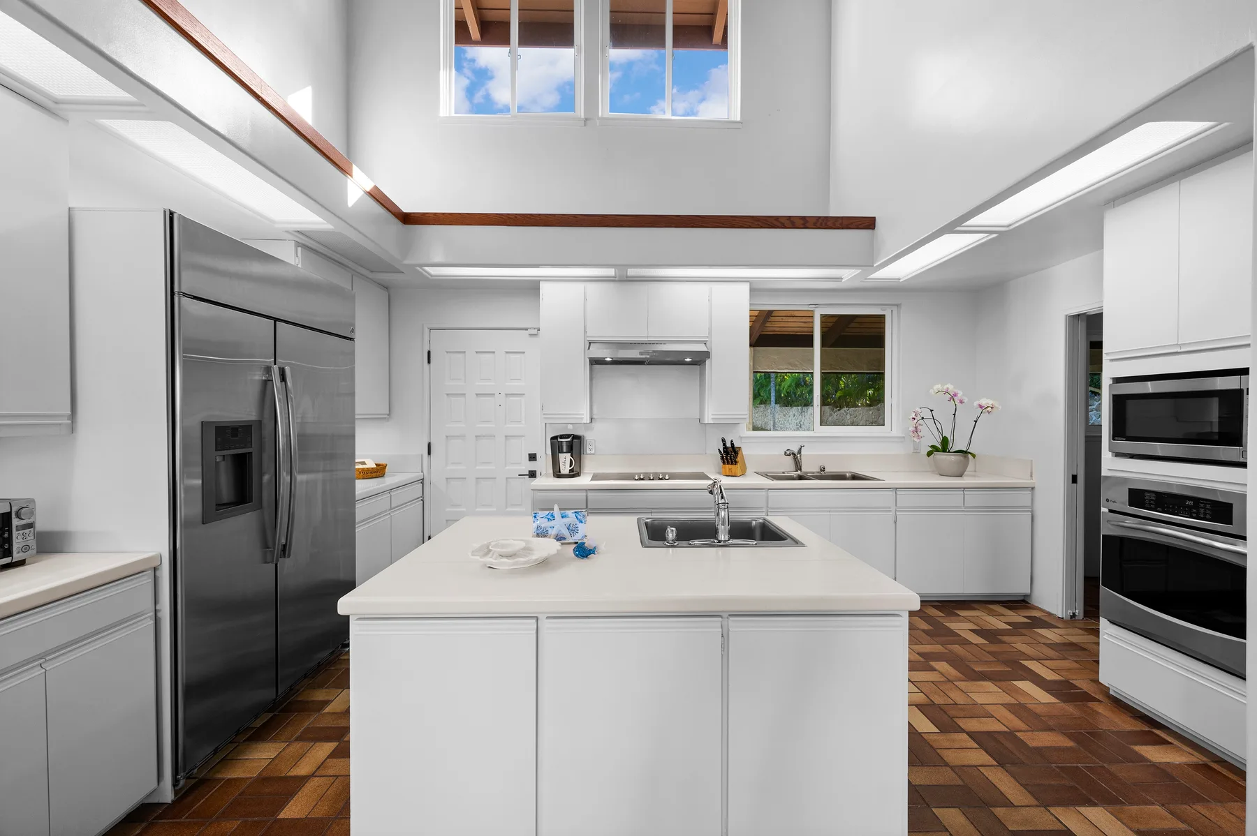 A bright kitchen with white cabinets, stainless steel appliances, and a large central island.