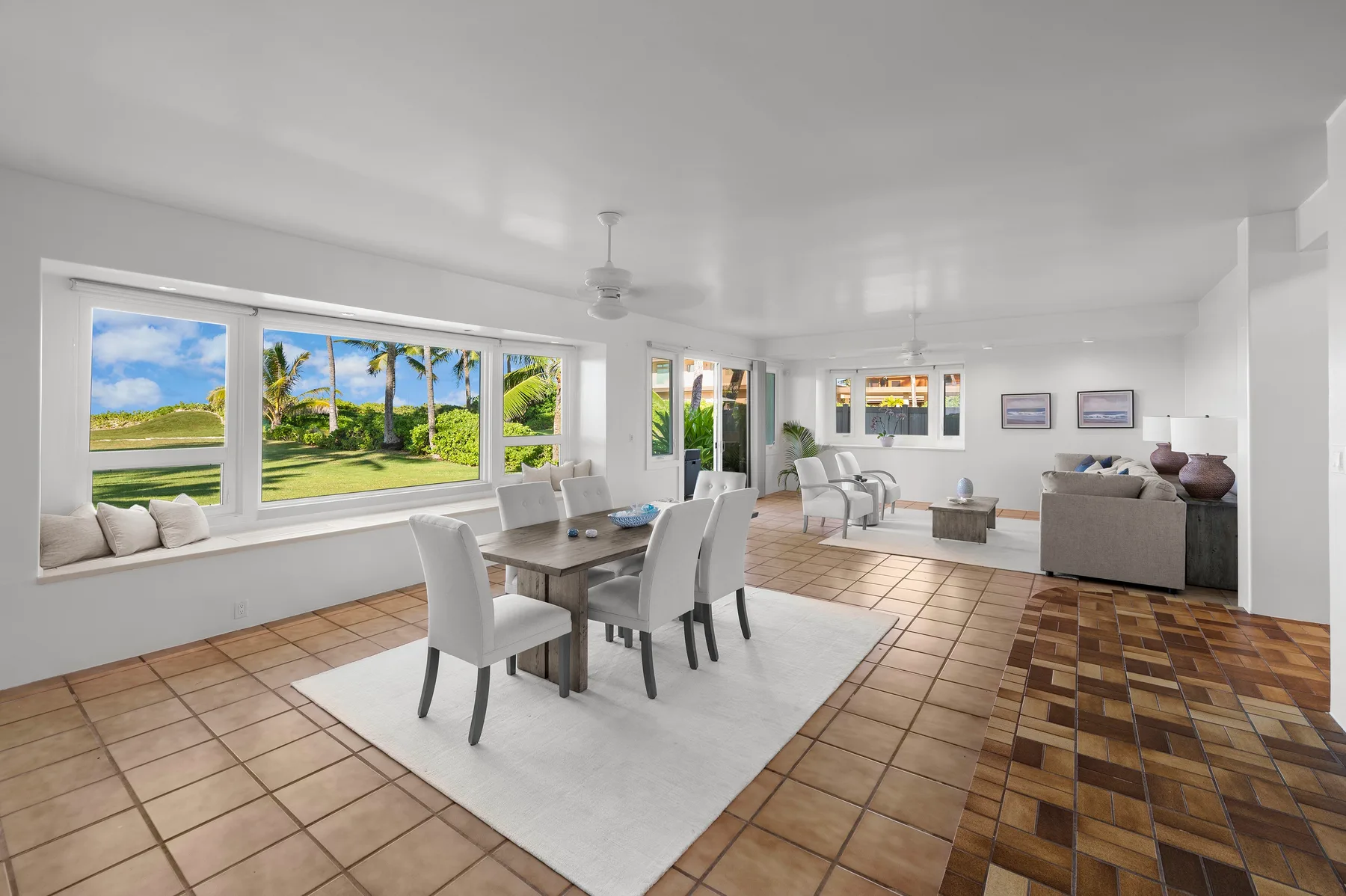 A bright living and dining room with a table, seating, and large windows.