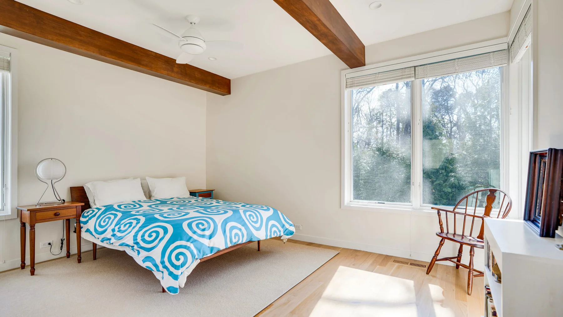 Un dormitorio con una cama bajo vigas de madera expuestas en el techo.