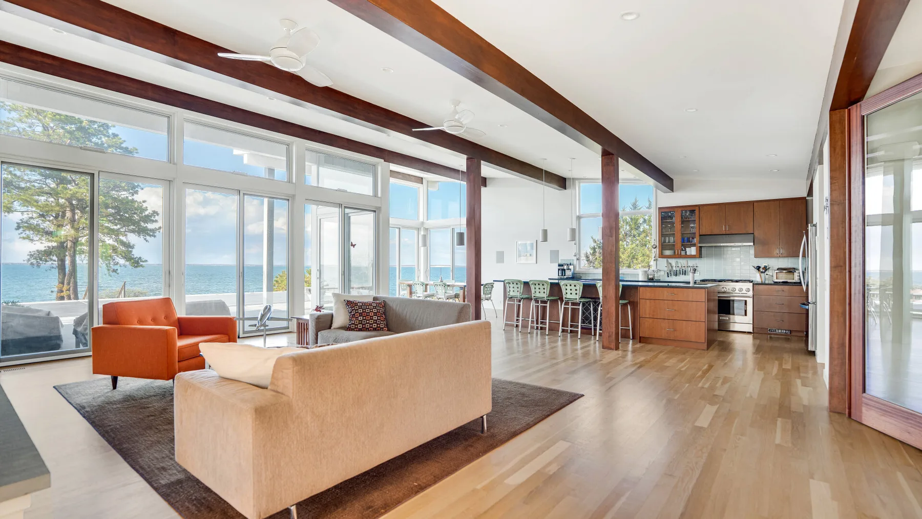Una sala de estar luminosa y abierta con grandes ventanas y una cocina.