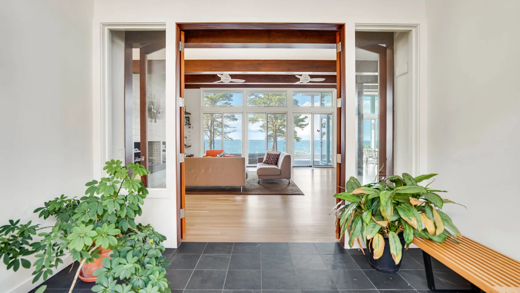Una sala luminosa se abre a una vista frente al agua, con asientos junto a las ventanas.