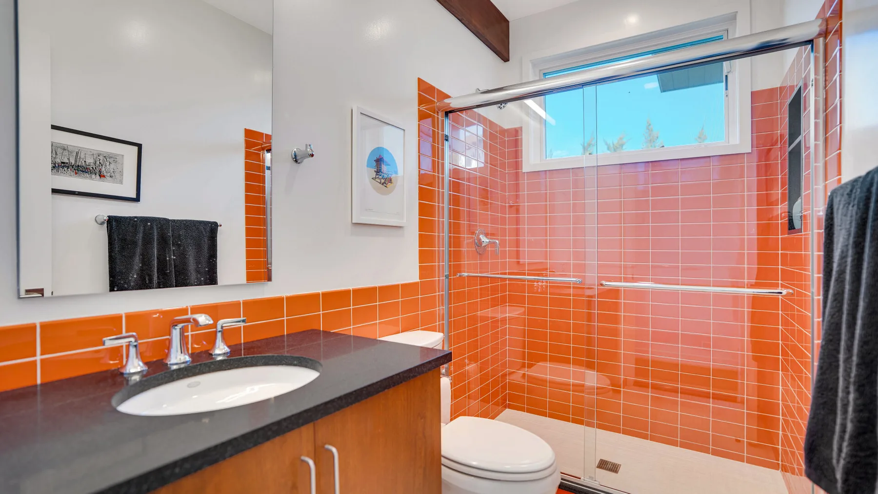 Un baño con paredes de azulejos naranjas, un lavabo y una ducha.