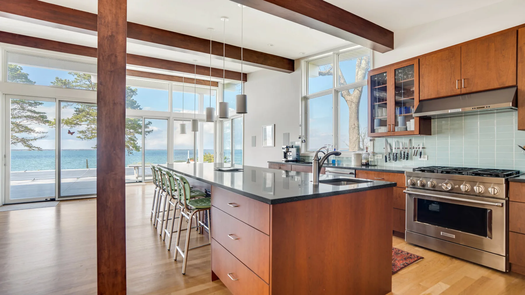 Una cocina abierta y luminosa con una isla central y grandes ventanas con vistas al agua.