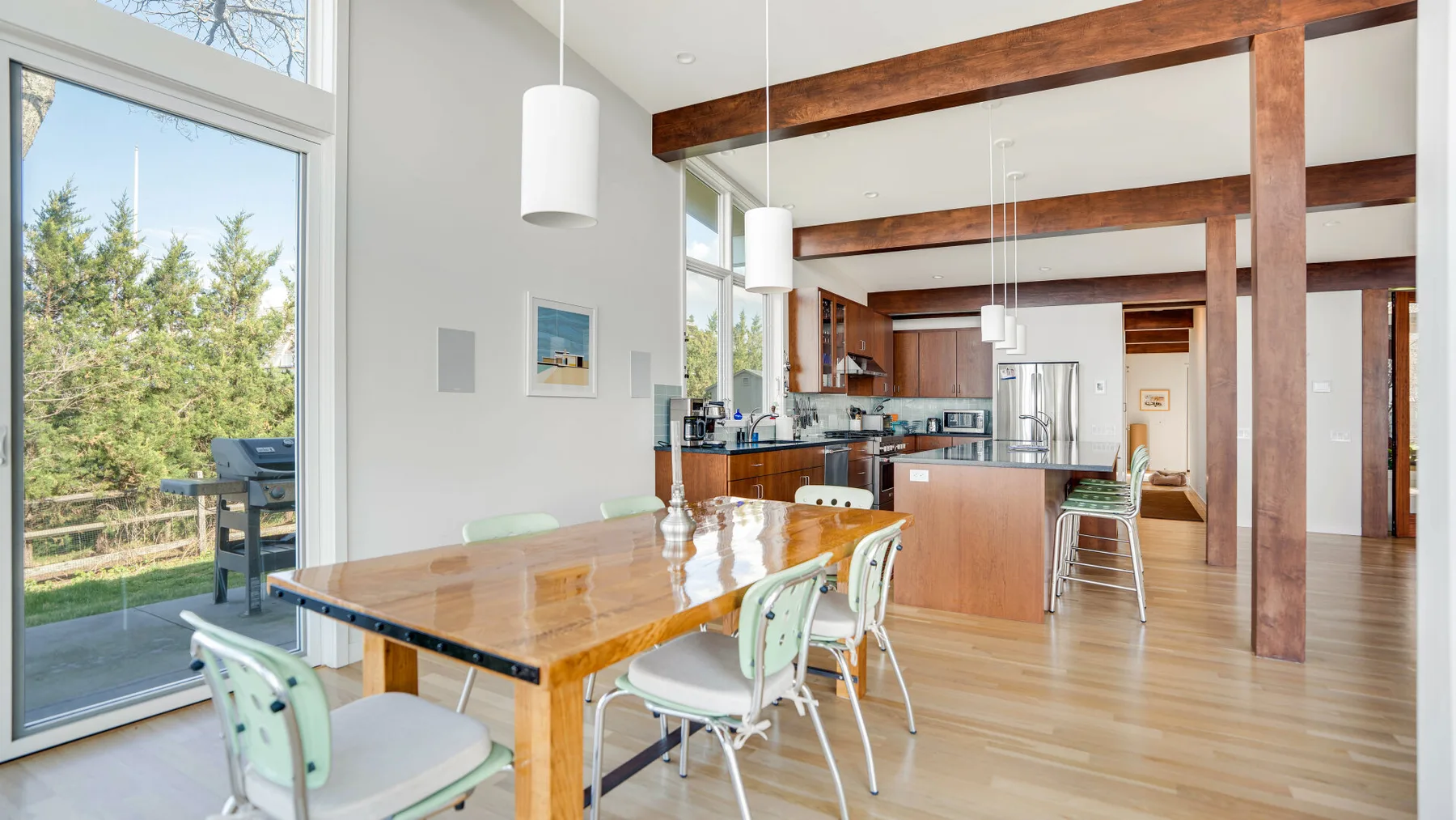 Un comedor y cocina de concepto abierto, luminosos, con grandes ventanas y vigas de madera a la vista.
