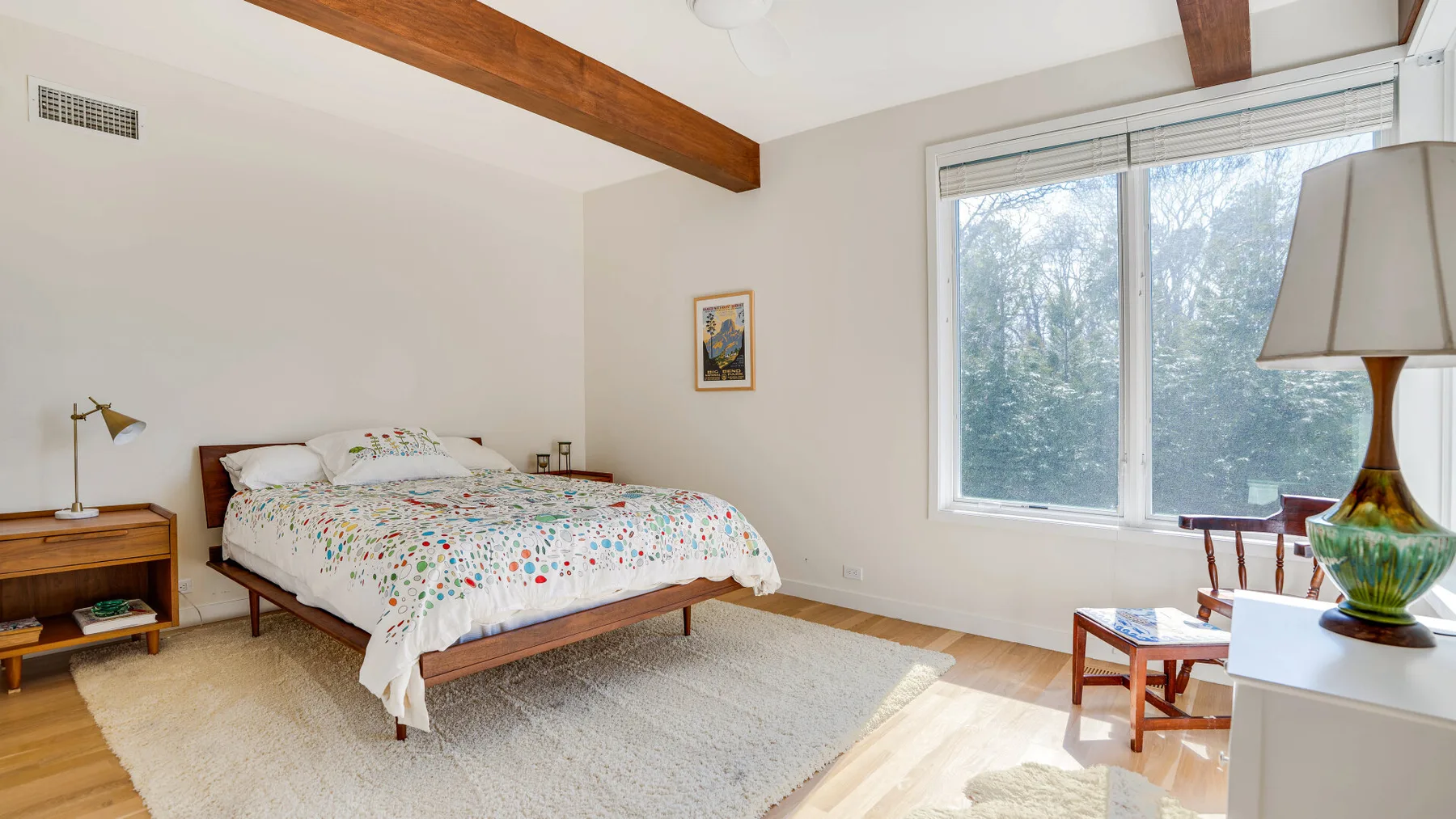 Un dormitorio con una cama, una ventana grande y una alfombra.