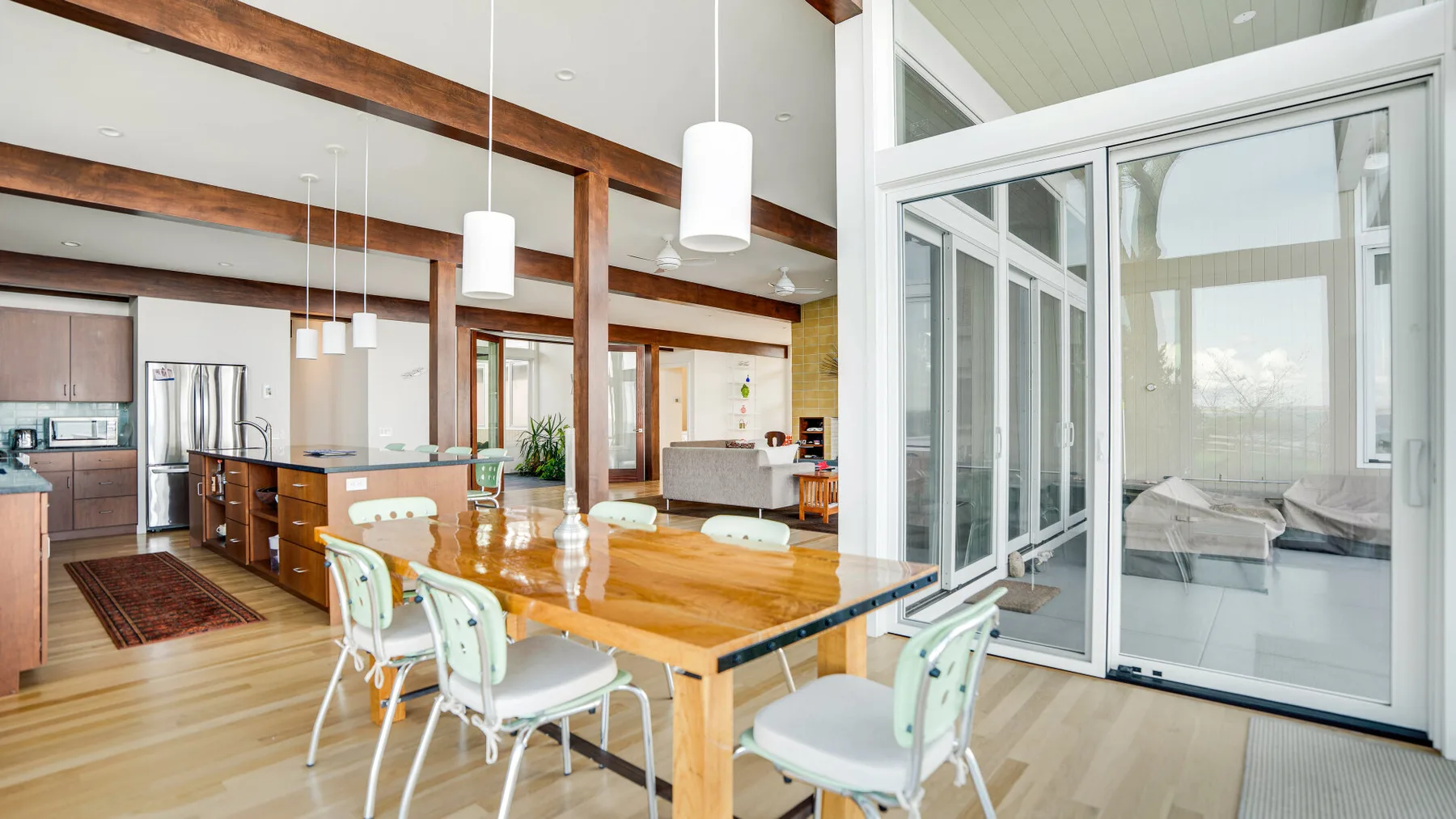 Un comedor luminoso con una mesa de madera junto a una sala acristalada.