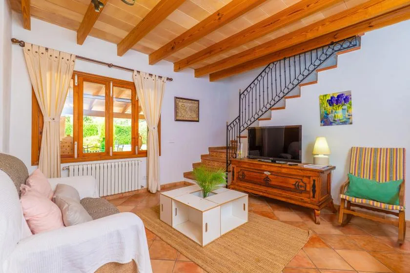 A living room with a television, coffee table, and staircase.