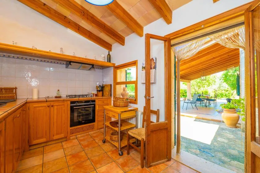 A kitchen opens onto a bright outdoor patio through an open doorway.