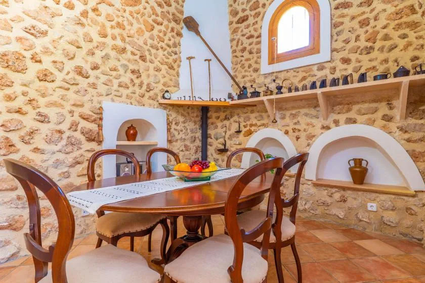 A dining area with a wooden table and chairs beside stone walls.