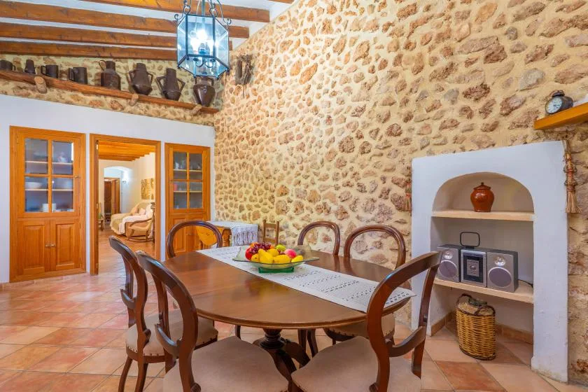 A rustic dining room with a wooden table and chairs beside a built-in fireplace.