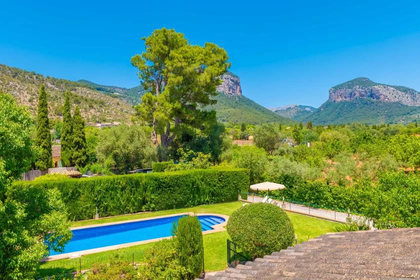 A swimming pool and landscaped garden sit beneath a mountain range.