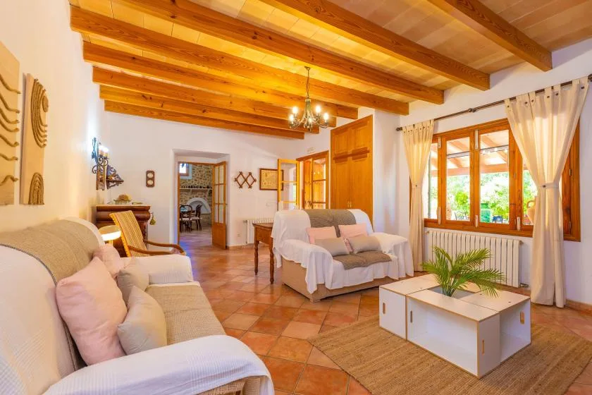 A bright living room with seating, wooden ceiling beams, and a large window.