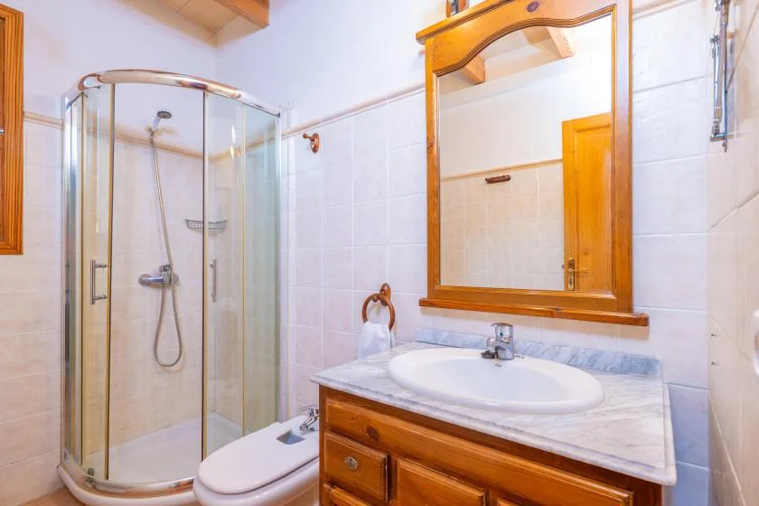 A tiled bathroom with a glass shower and a wooden vanity.