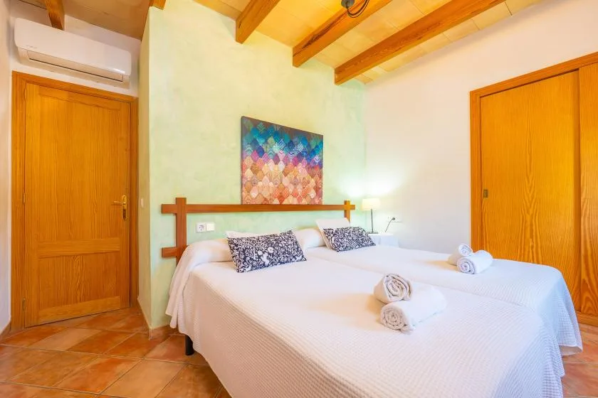 A bedroom with a double bed, colorful wall art, and exposed wooden ceiling beams.