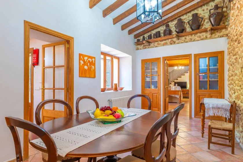 A dining room with a long wooden table and exposed ceiling beams.