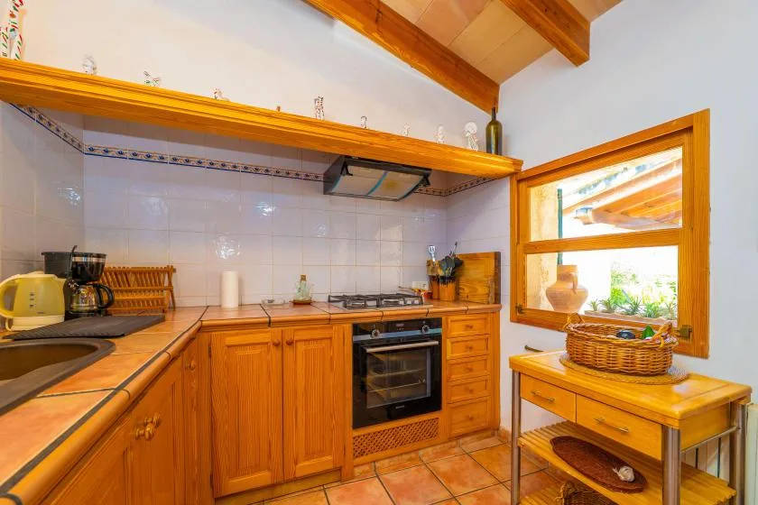 A rustic kitchen with wooden cabinets and a tiled countertop.