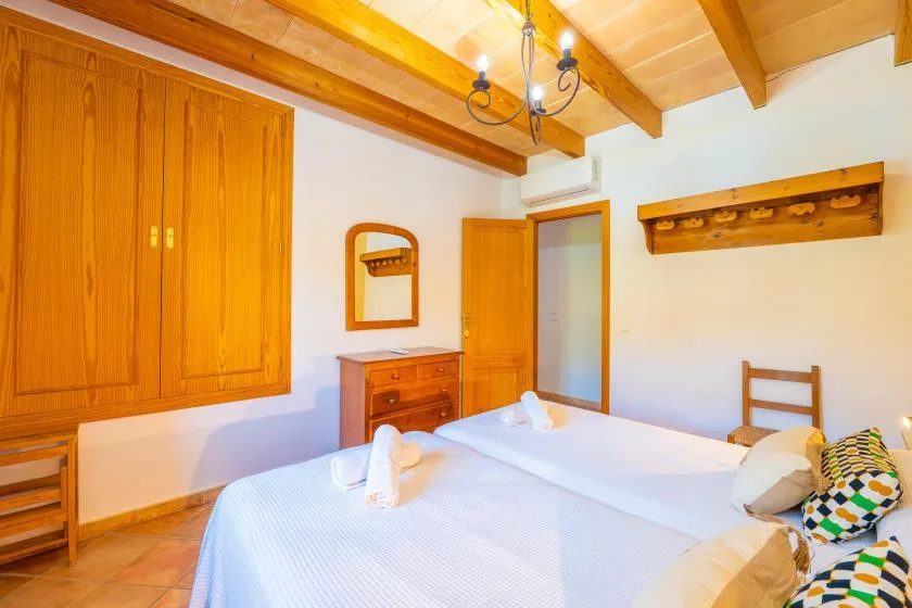 A bedroom with two beds, wooden wardrobes, and exposed ceiling beams.