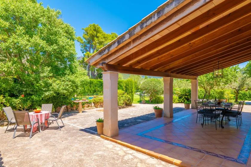 A shaded outdoor patio with dining tables and garden views.