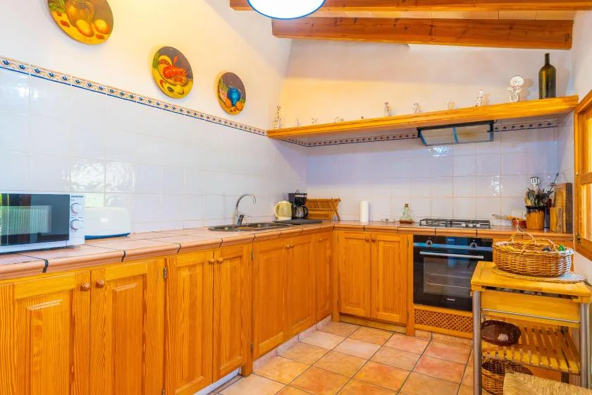 A kitchen with wooden cabinets, tiled walls, and a countertop.
