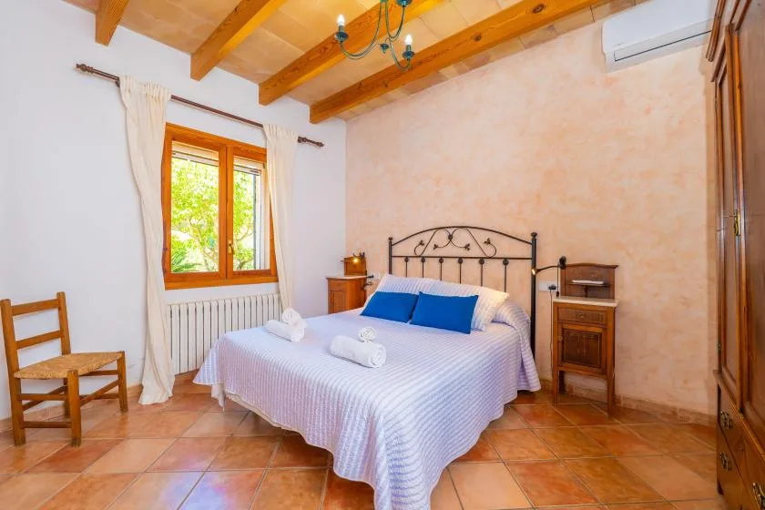 A bedroom with a bed beneath exposed wooden ceiling beams.