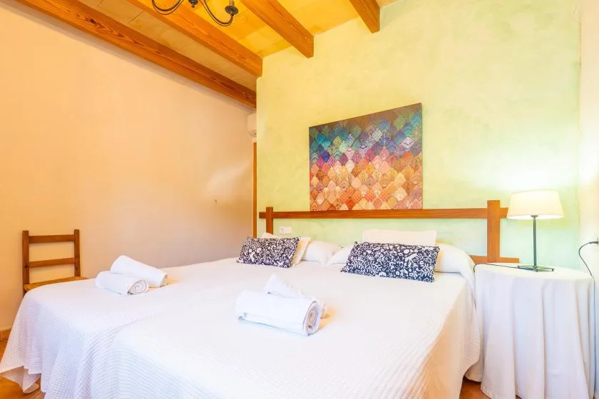 A bedroom with a white bed, colorful wall art, and a bedside lamp.